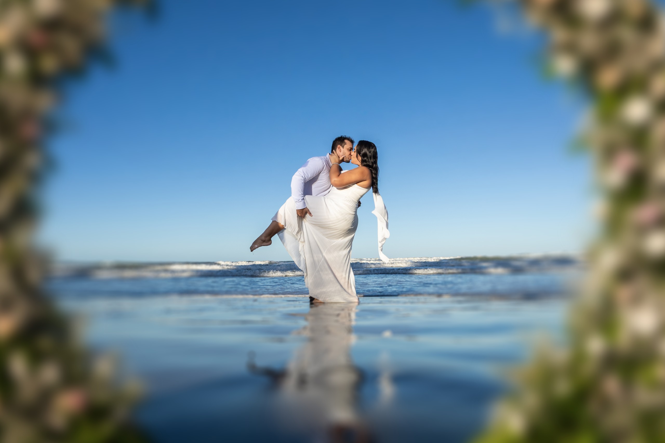 Andreza e Igor sob o arco de flores na praia